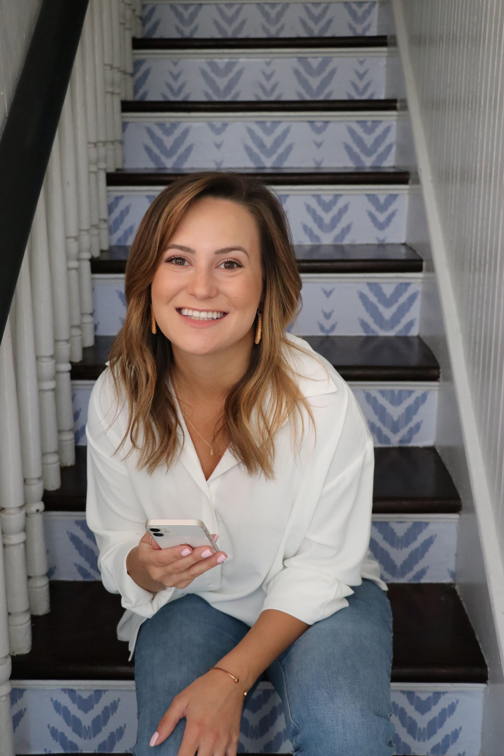 woman sitting on steps smiling with a phone